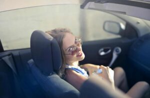 Young female driver in a car smiling.